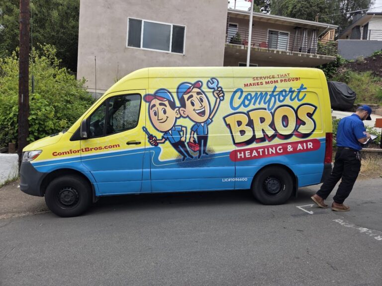 Yellow Comfort Bros Heating & Air van parked on street; man in blue uniform stands beside it, writing on a clipboard.